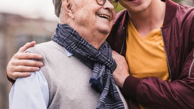 Un hombre mayor y un joven se abrazan sonriendo.