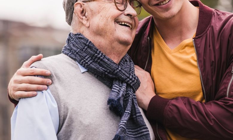 Un hombre mayor y un joven se abrazan sonriendo.