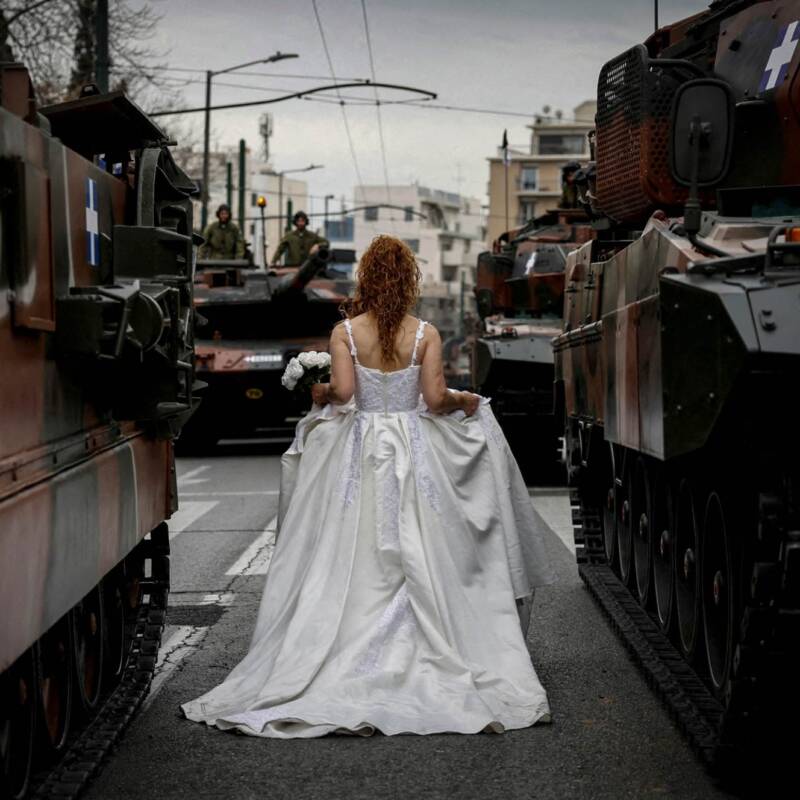 Una novia participa en una sesión de fotos mientras camina junto a vehículos del Ejército helénico antes de un desfile militar que conmemora el Día de la Independencia de Grecia, en Atenas, Grecia, el 25 de marzo de 2025. REUTERS/Louiza Vradi